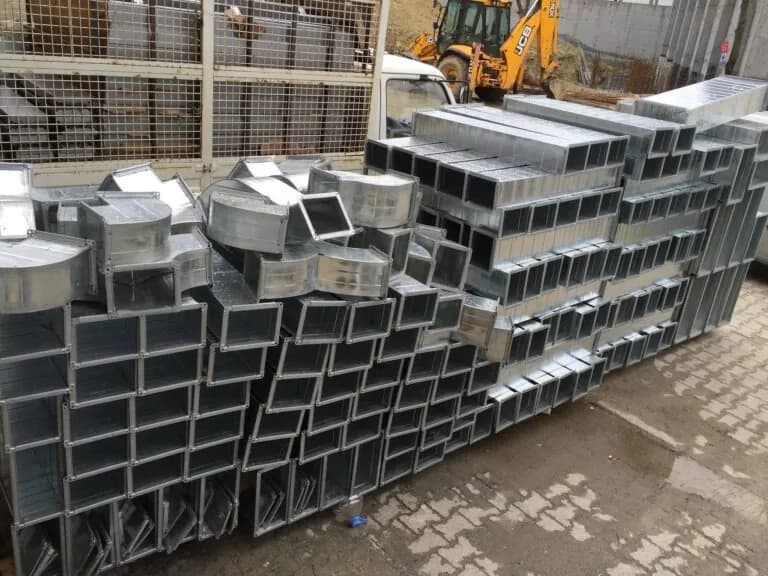 Projeye göre imal edilmiş dikdörtgen galvaniz kanal parçaları, dirsekler ve bağlantı elemanları; sevk için istiflenmiş hâlde.